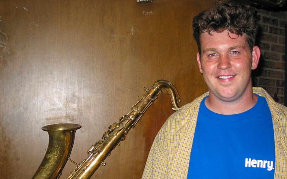 man standing in front of saxophone hanging on wall